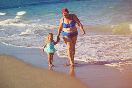 grandmother with little girl go swim at beach, active retirementの写真素材