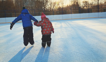 little girl and boy larning to skate in winter nature