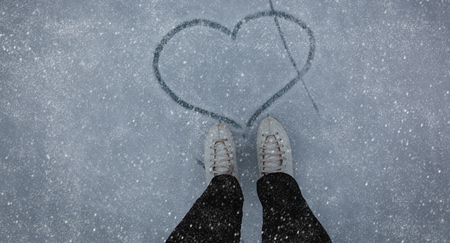 love skating concept - feet in skates and heart on snow natureの写真素材