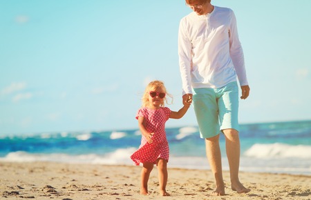 father and cute little daughter walk at beachの写真素材