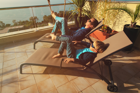 Dad and son relax on balcony terraceの写真素材