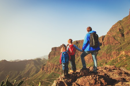 father and two kids hiking climbing in mountainsの写真素材