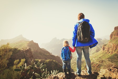 father and little daughter hiking climbing in mountainsの写真素材