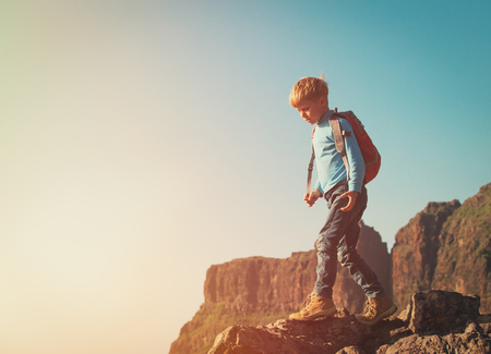 little boy with backpack hiking climbing in scenic mountainsの写真素材