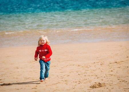 cute little girl running on winter beachの写真素材