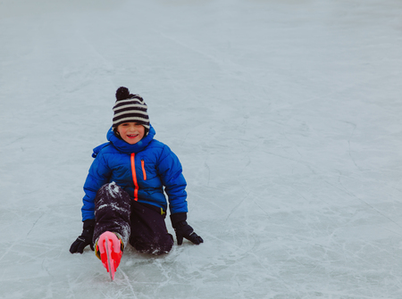happy little boy learning to skate in winter