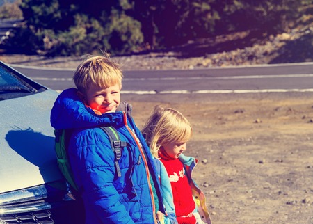 little boy and toddler girl travel by car on the roadの写真素材