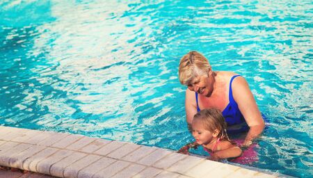 Grandmother teaching granddaughter to swimの写真素材