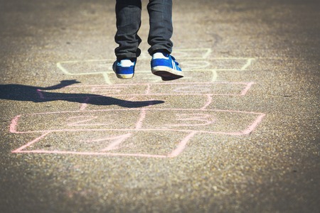 little boy playing hopscotch on playgroundの写真素材