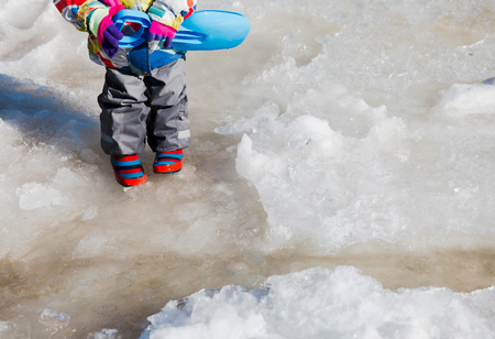 little girl playing in water puddle in springの写真素材