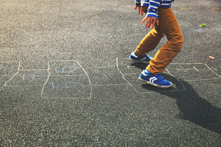kid playing hopscotch on playground outdoorsの写真素材