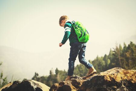 little boy with backpack hiking in mountainsの写真素材