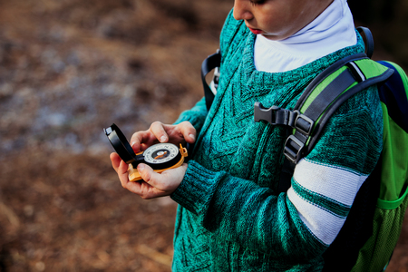 little boy travels with compass in green forestの写真素材