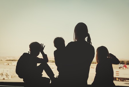 family travel- mother with three kids looking at planes in airportの写真素材