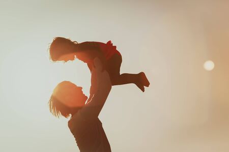 Father and little daughter silhouettes at sunsetの写真素材