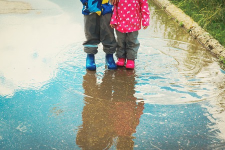 little boy and girl play in water puddleの写真素材