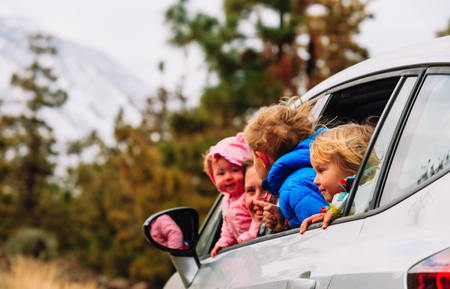 family travel by car- happy mother with kids driving in mountainsの写真素材