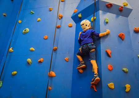 little boy climbing wall in sport centerの写真素材
