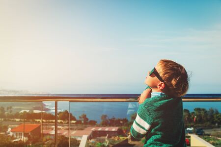 little boy relaxed looking at sun on balcony at seaの写真素材