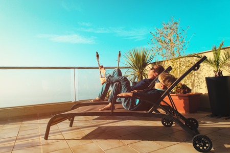 Dad and son relax on balcony terraceの写真素材