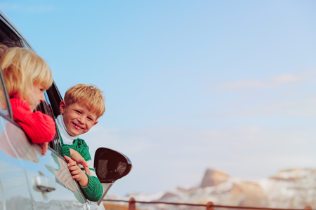 happy little boy and girl travel by car in mountainsの写真素材