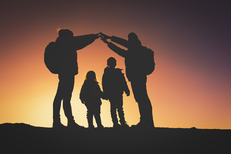 Silhouettes of family with two kids hiking at sunsetの写真素材