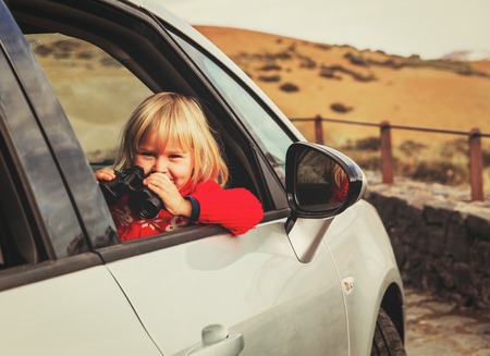 little girl looking through binoculars travel by carの写真素材