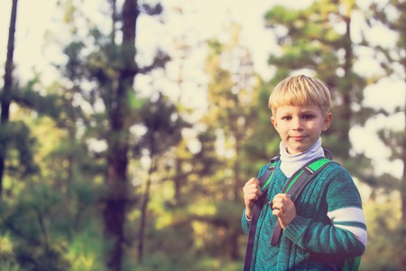 happy little boy with backpack travel in green forestの写真素材
