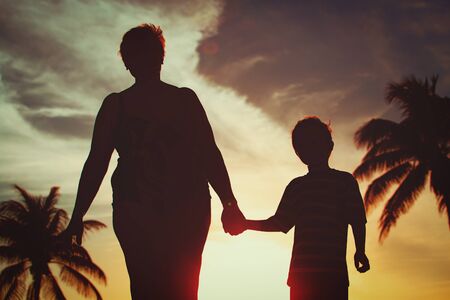 Silhouette of grandmother and child at tropical beachの写真素材