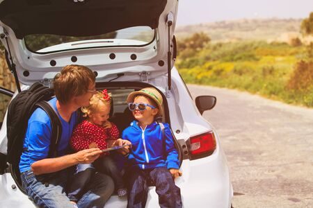 family car travel - father with two kids looking at map on roadの写真素材