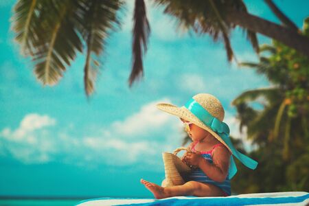 cute little girl in big hat on tropical beachの写真素材