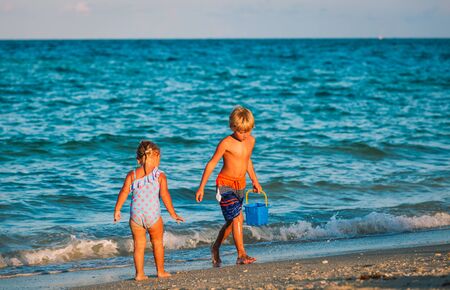 little boy and girl play with water on beachの写真素材