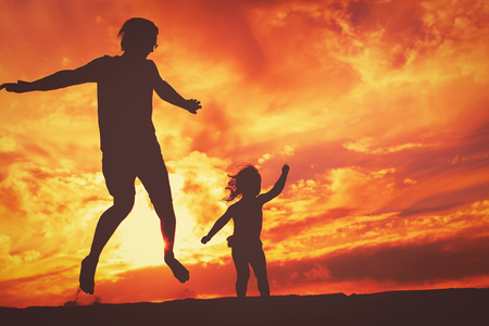 Father and little daughter silhouettes play at sunsetの写真素材