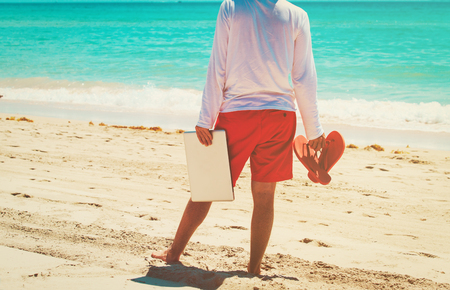 Young man with laptop on summer beachの写真素材