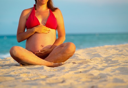 Happy pregnant woman at tropical beachの写真素材