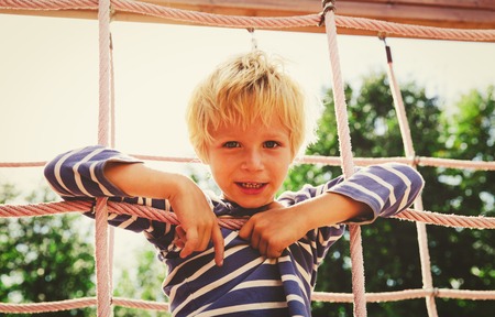 little boy playing on monkey bars at playgroundの写真素材
