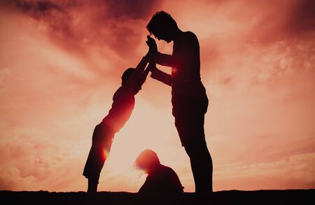 father and two kids playing on sunset skyの写真素材