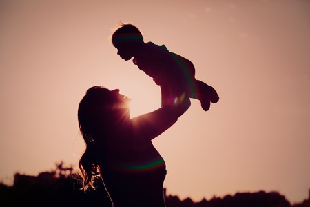 mother and little newborn daughter silhouettes at sunsetの写真素材