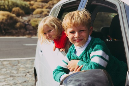 happy little boy and girl travel by car on roadの写真素材