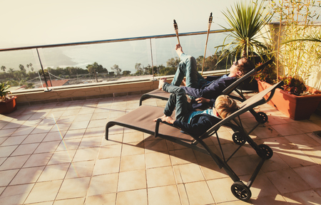 Dad and son relax on balcony terraceの写真素材