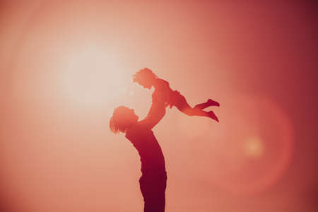 Father and little daughter silhouettes play at sunset