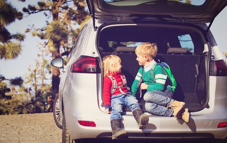 little boy and girl travel by car on road in natureの写真素材