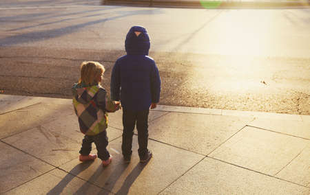 little boy and girl holding hands in sunset cityの写真素材