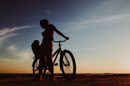 Silhouette of mother and baby biking at sunsetの写真素材
