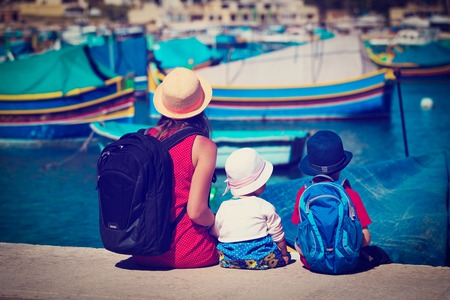 mother and two kids looking at traditional boats in Maltaの写真素材