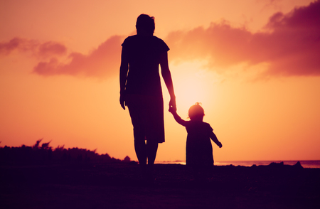 mother and little daughter walking at sunsetの写真素材