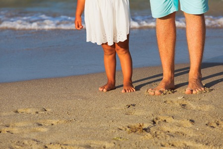 Close up of father and little daughter feet on beachの写真素材