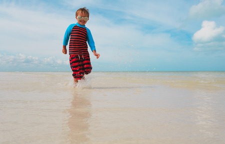 little boy enjoy play with water on beachの写真素材