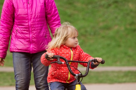 mother teaching little daughter to ride bicycleの写真素材