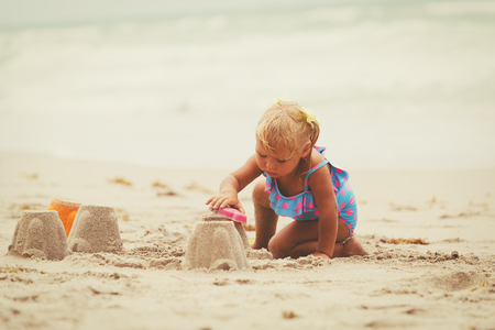 cute little girl play with sand on beachの写真素材